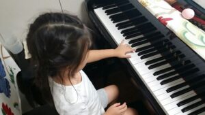 女の子がピアノに手を置く姿