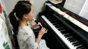 ピアノの前でリコーダーを吹く女の子の画像