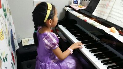 紫のドレスを着てピアノを弾く子供