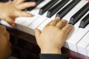 ピアノの鍵盤と子供の手の画像