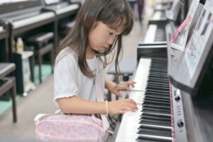 楽器売り場で電子ピアノを弾く女の子の画像