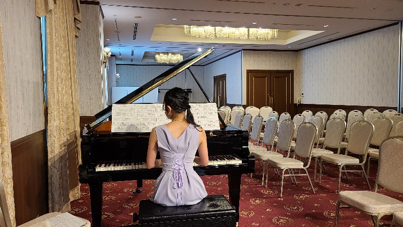 パープルのドレスを着てピアノを弾く女性の画像