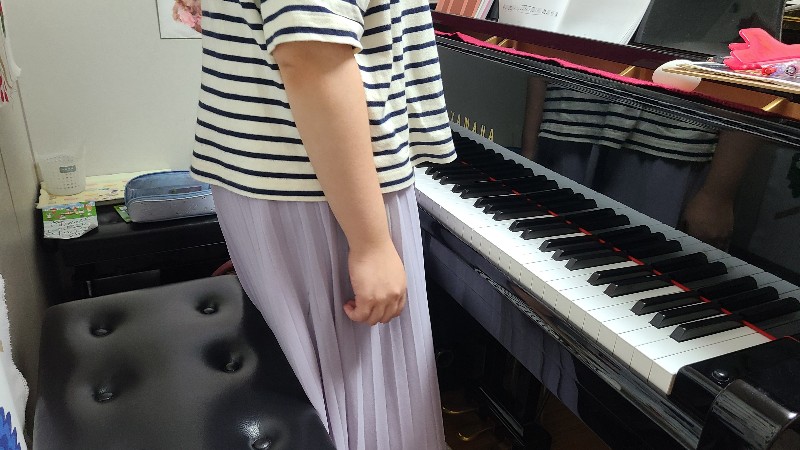 ピアノの前に立つ女性の画像
