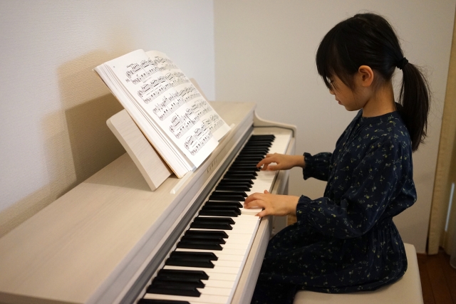お家で電子ピアノを練習する女の子の画像
