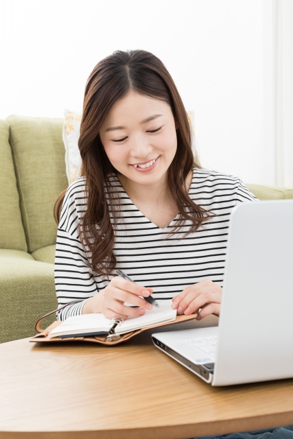 パソコンでピアノレッスンのスケジュールを確認する女性の画像